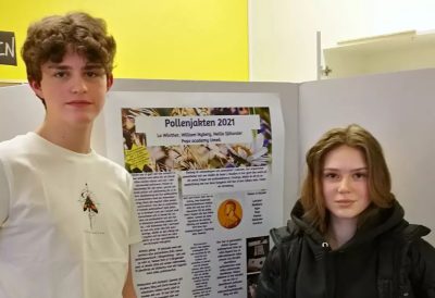 Två elever står framför en poster med elevernas resultat av projektet Pollenjakten 2021.