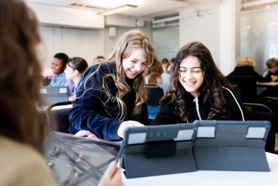 Två elever på Pops Academy studerar tillsammans vid läsplattor.