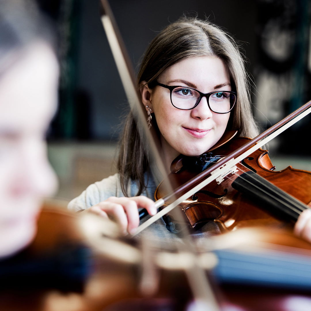 Två elever på Pops Academy spelar fiol tillsammans.