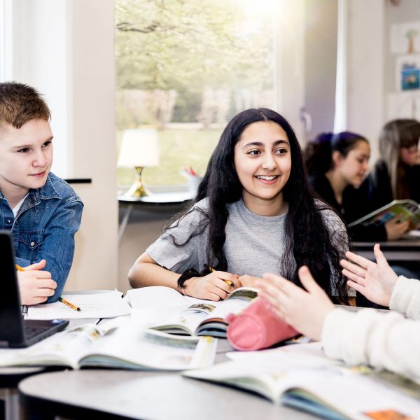 Tre elever på Pops Academy jobbar tillsammans i klassrummet.