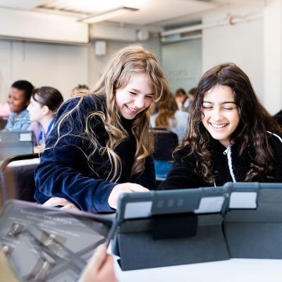 Två elever på Pops Academy studerar tillsammans vid läsplattor.