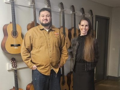 Rektor Johanna och Daniel Nilo framför en vägg med gitarrer