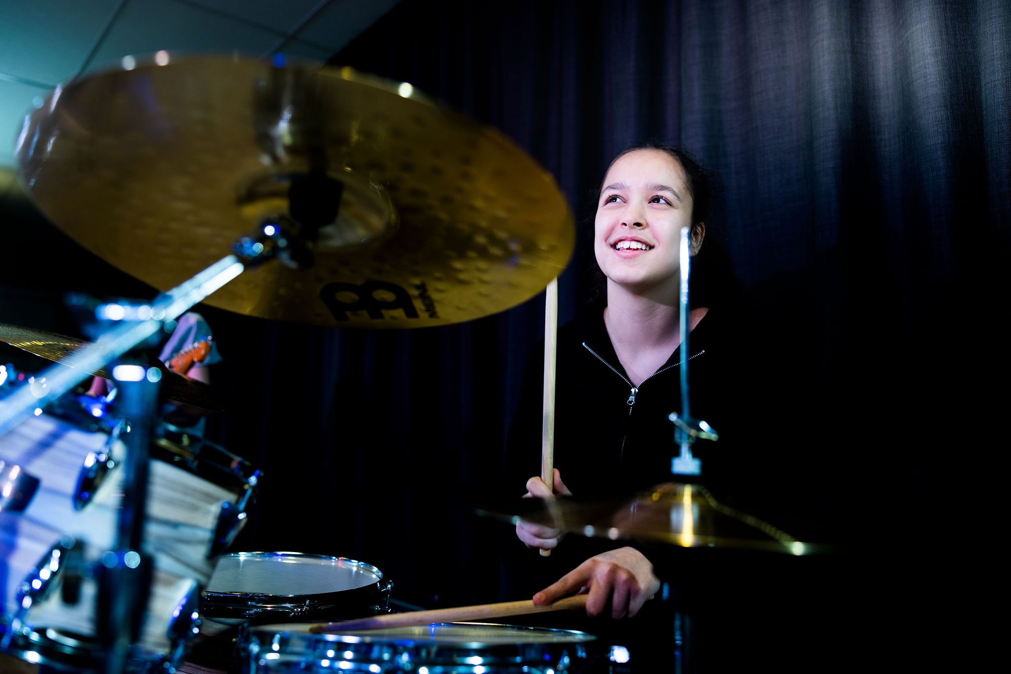 Elev på Pops Academy spelar trummor på scen.
