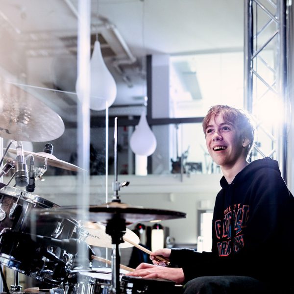 Elev på Pops Academy spelar trummor på scen.