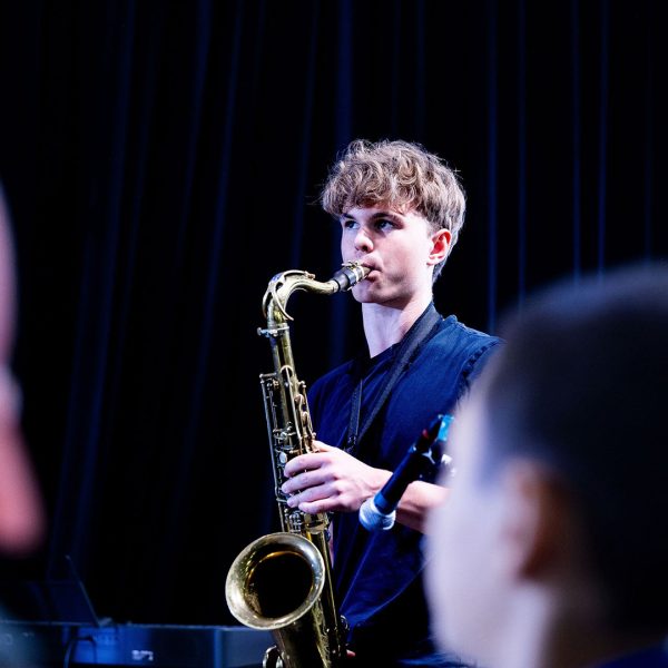 Elev på Pops Academy spelar saxofon på scen.