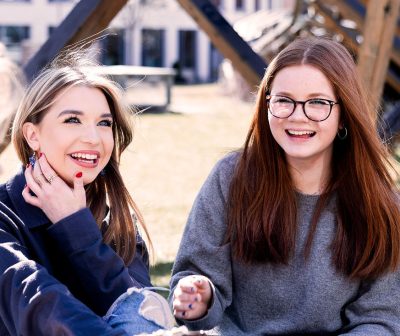 Två elever sitter på gräset utanför skolan Pops Academy Stockholm