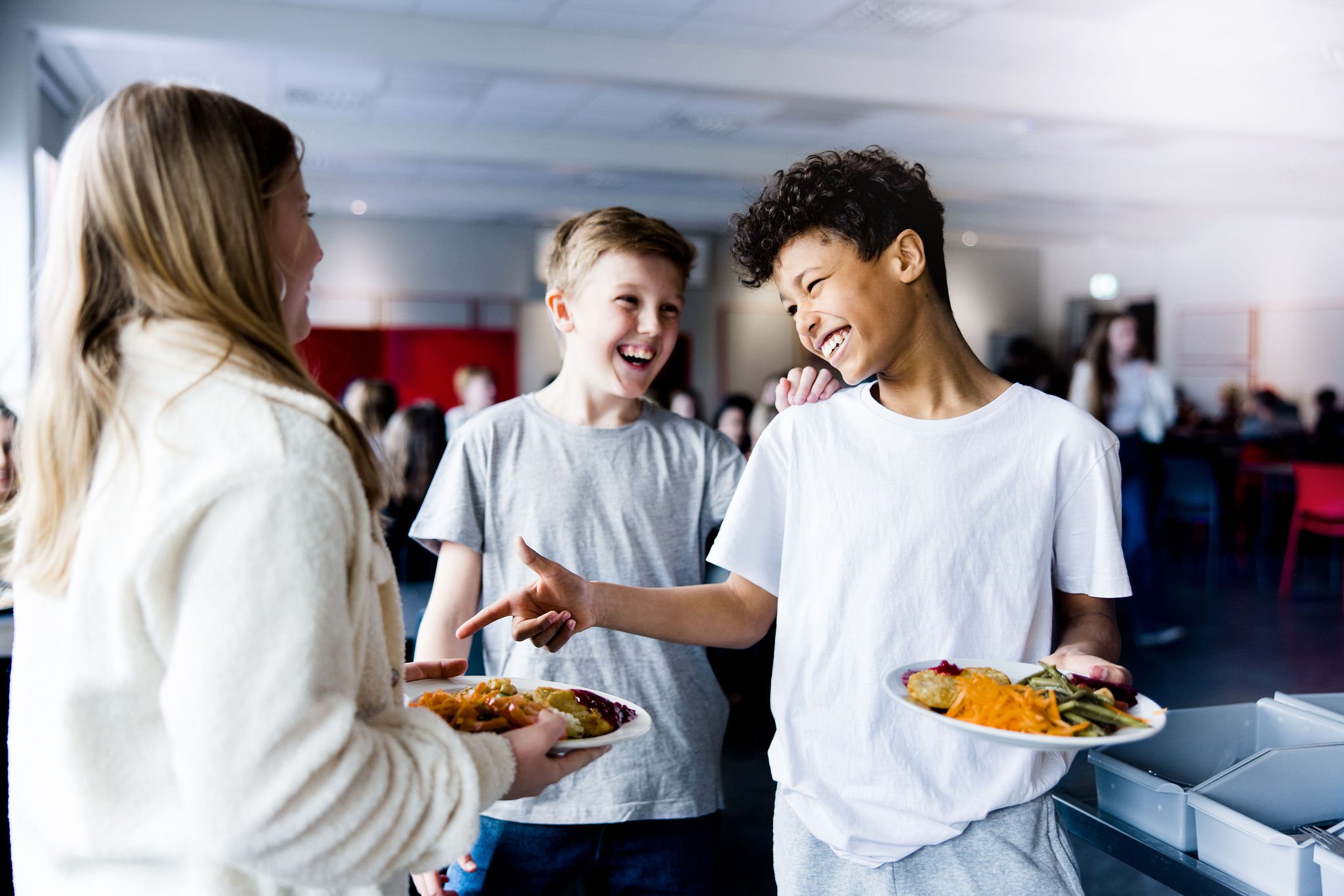 Tre elever på Pops Academy står tillsammans i matsalen och ska äta.