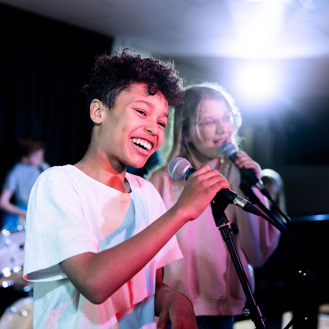 Elever på Pops Academy sjunger tillsammans på scen.